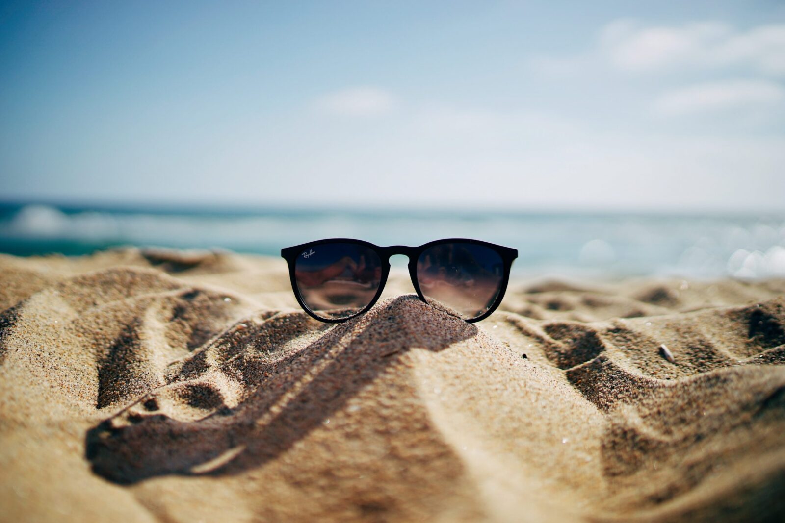 Das Bild zeigt eine Sonnenbrille am Strand im Sand.
