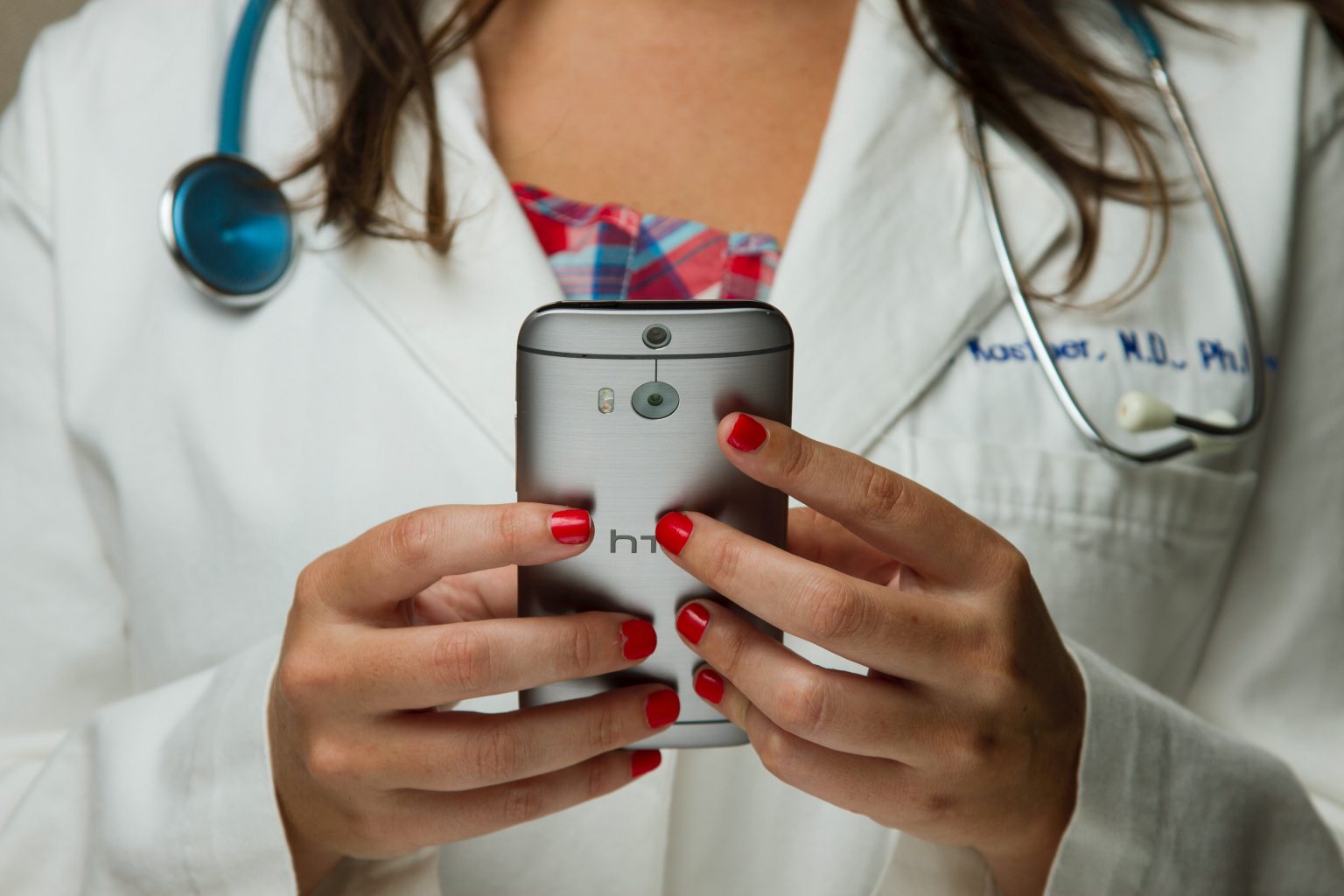 Das Bild zeigt eine junge Ärztin mit Handy.